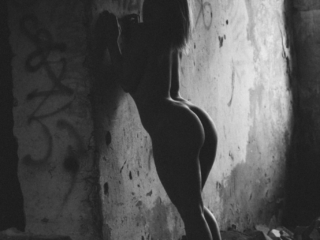 Kunstilised aktifotod mahajäätud hoones müüri vastas paljas naine